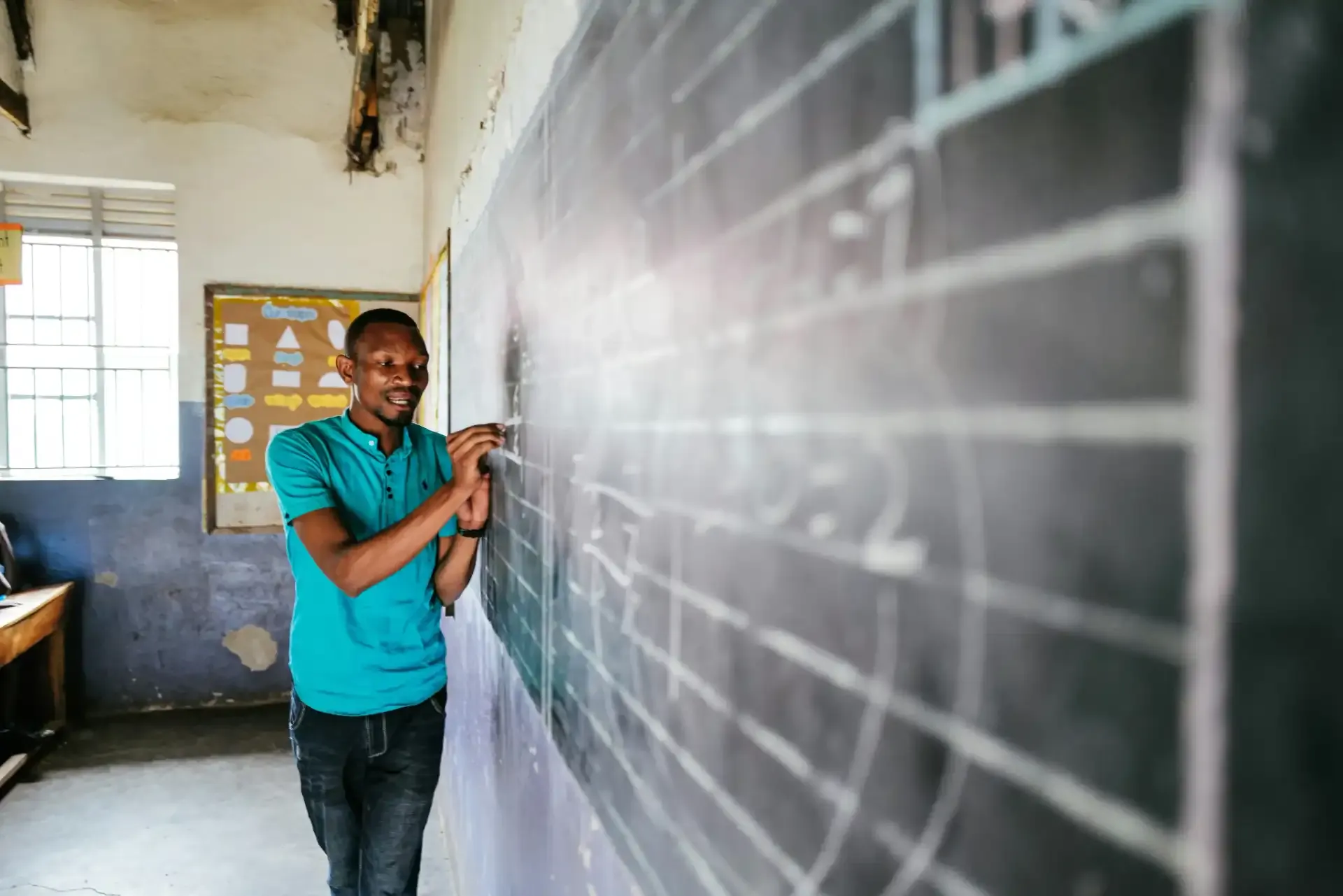 Student standing in a classroom by a chalkboard