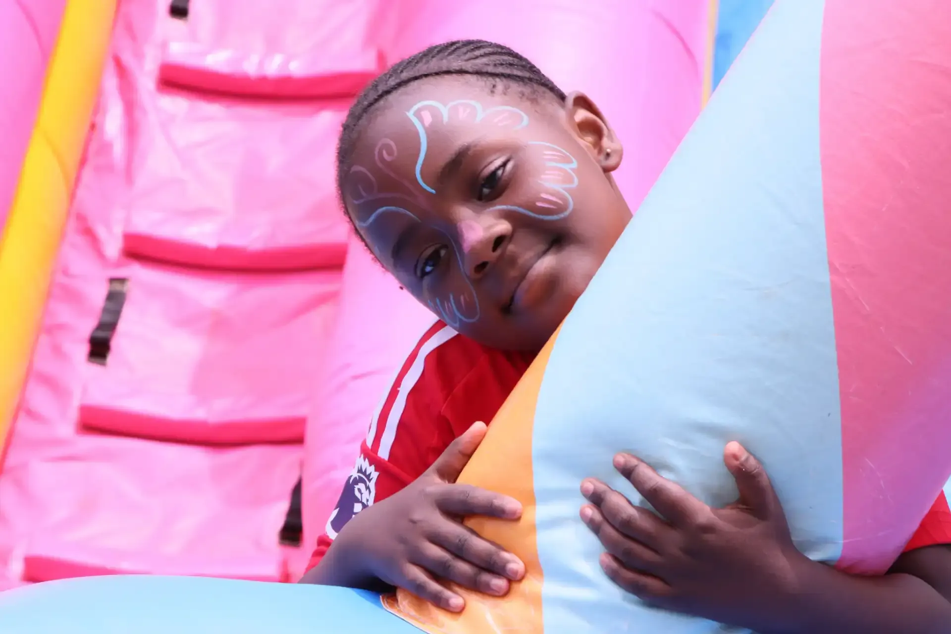 A young child with colorful face paint smiling